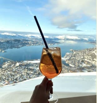 Sklenice s drinkem nad panoramatem města a fjordu